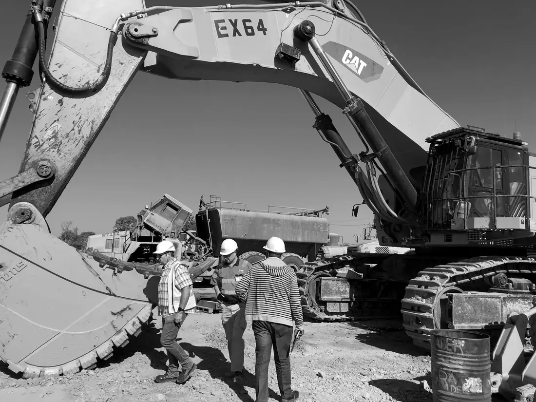TMS and mine team members next to the MTG bucket of a Caterpillar 6015 excavator on a mine in D.R. Congo