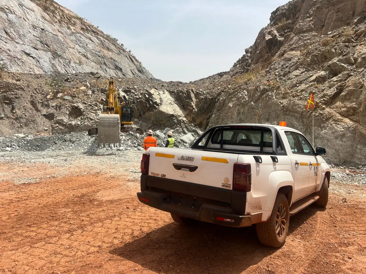 Site pickup parked in a cutting while an excavator works the rock face